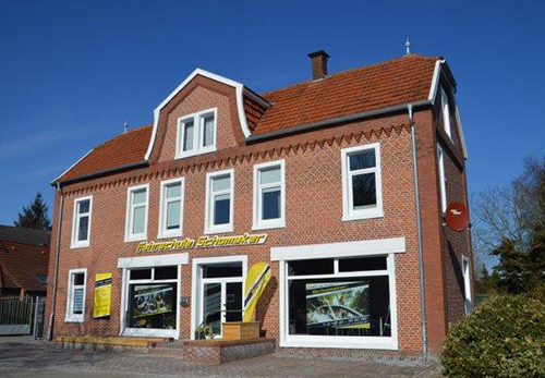 Backsteingebäude der Fahrschule Schomaker-Behrens am Hauptkanal links in Papenburg mit gelbem Fahrschul-Schild
